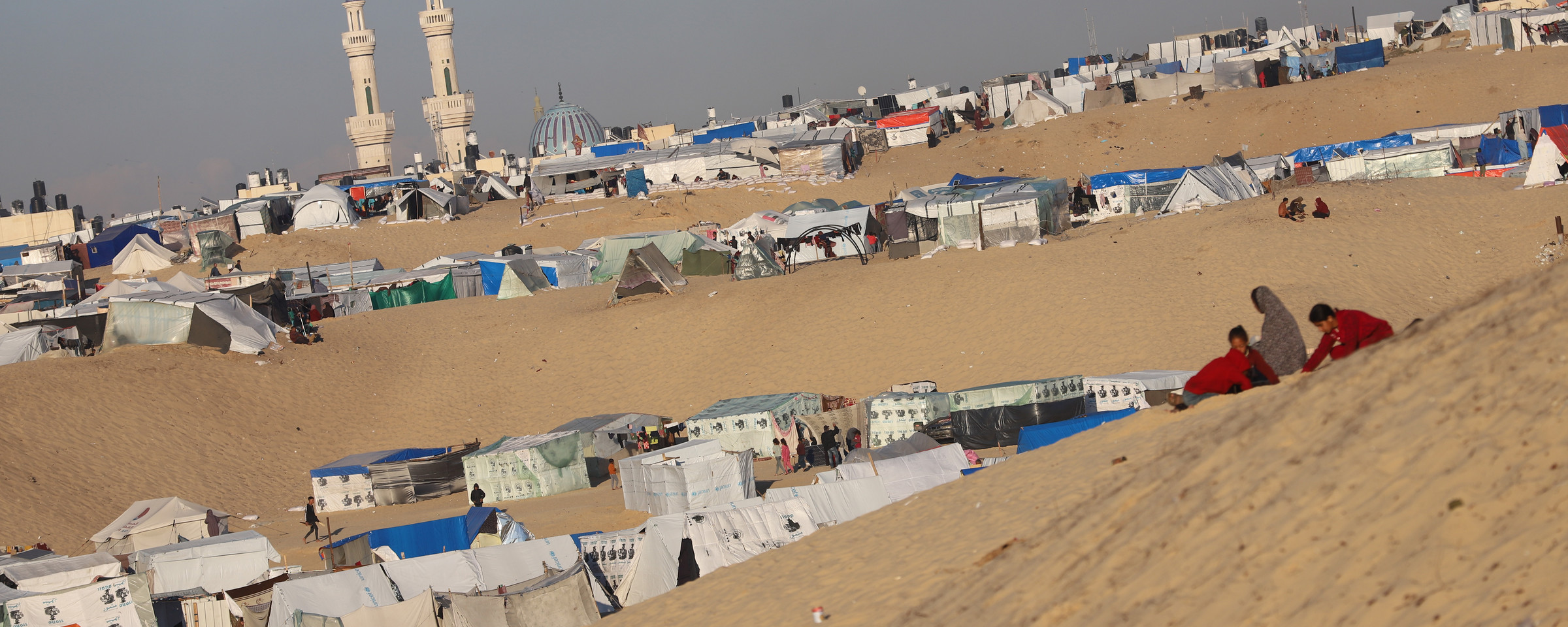 A daytime view of tents erected along a sandy desert hillside