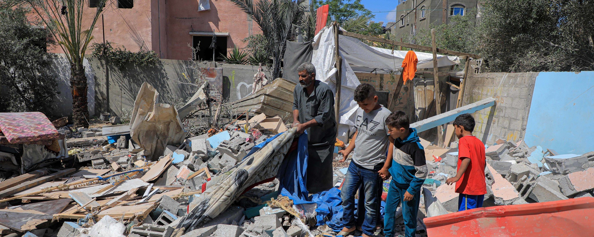 A man and three children stand on top of a pile of rubble