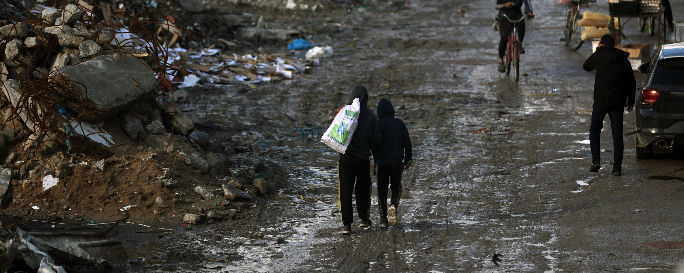 People wal;k past mountains of waste in Gaza