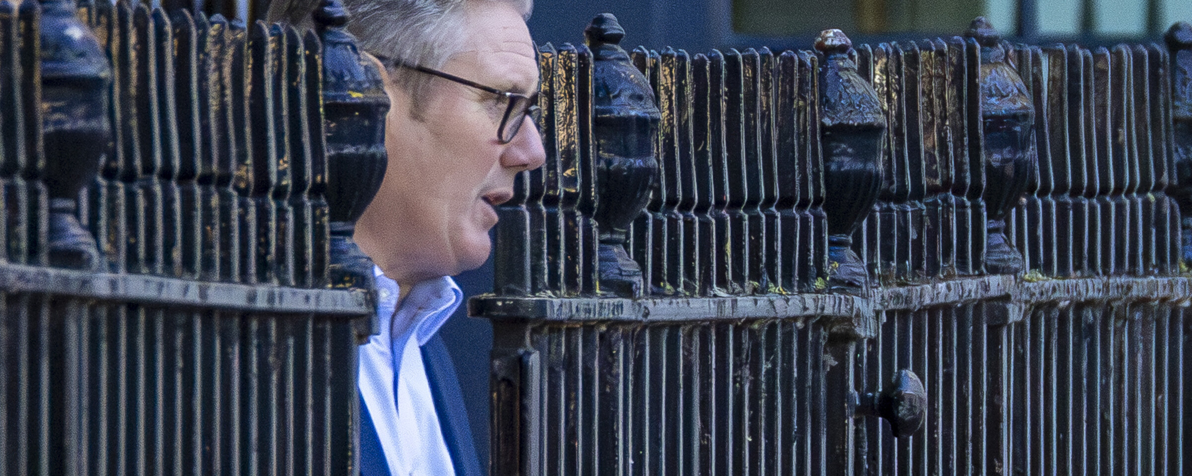 UK Prime Minister emerges from a metal fence