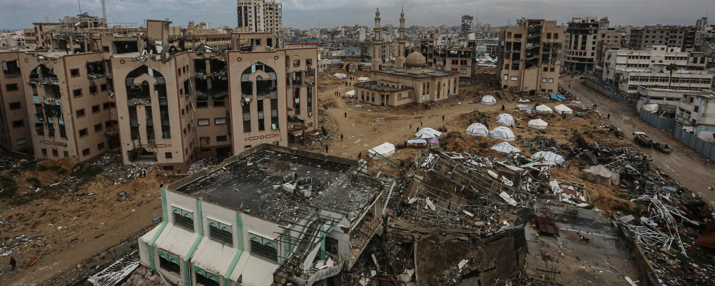 Several tents pitched in a severely destroyed campus with few buildings standing but damaged.