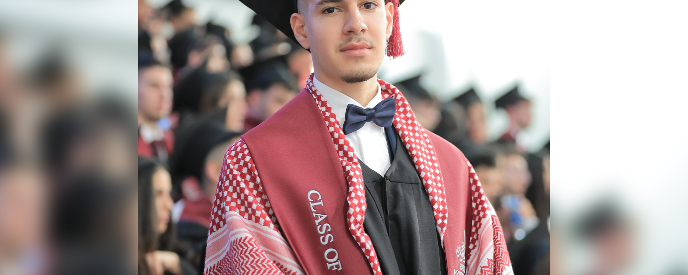 Young man wearing graduation cap and kuffiyeh is seen from chest up