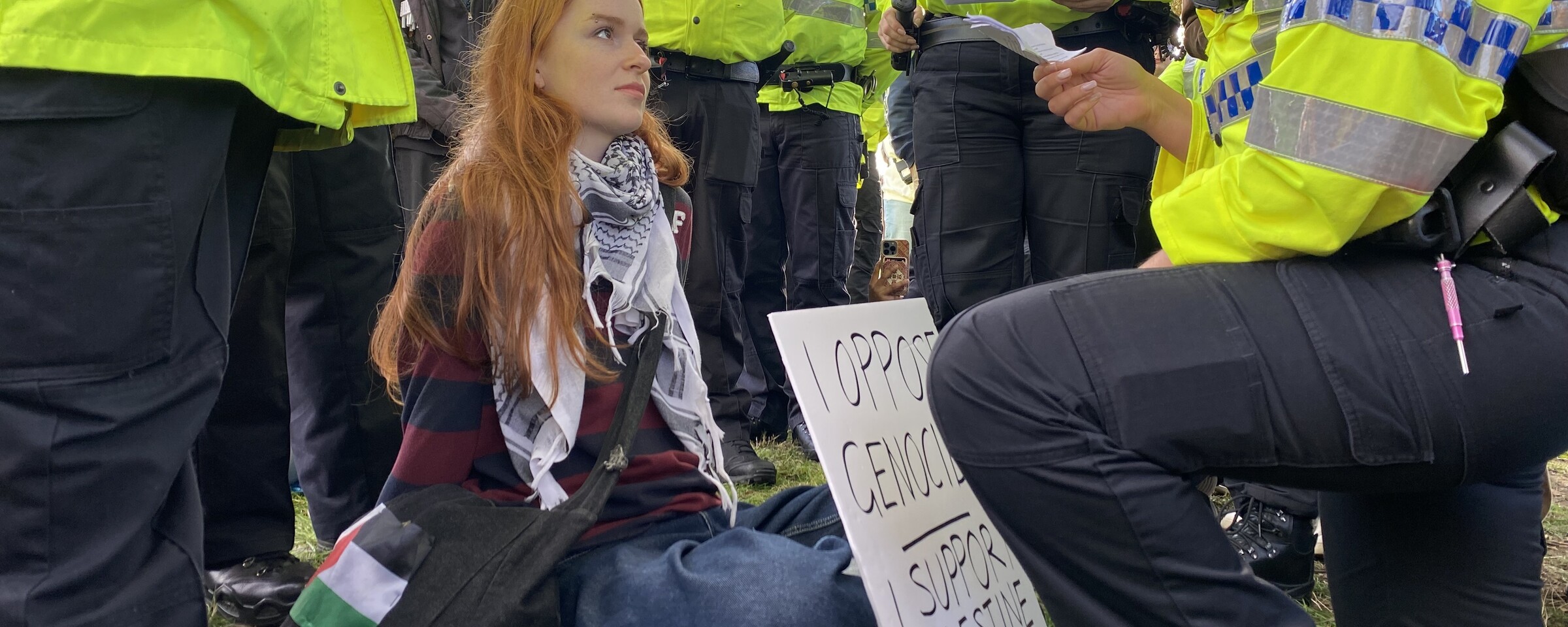 A woman holding a sign surrounded by police