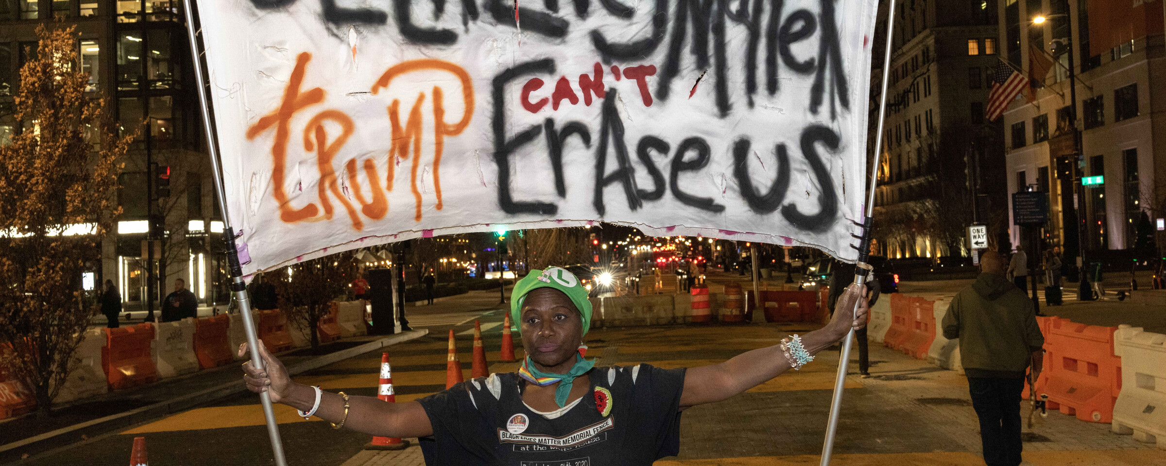 A protester holds a banner reading Black Lives Matter Trump Can't Erase Us