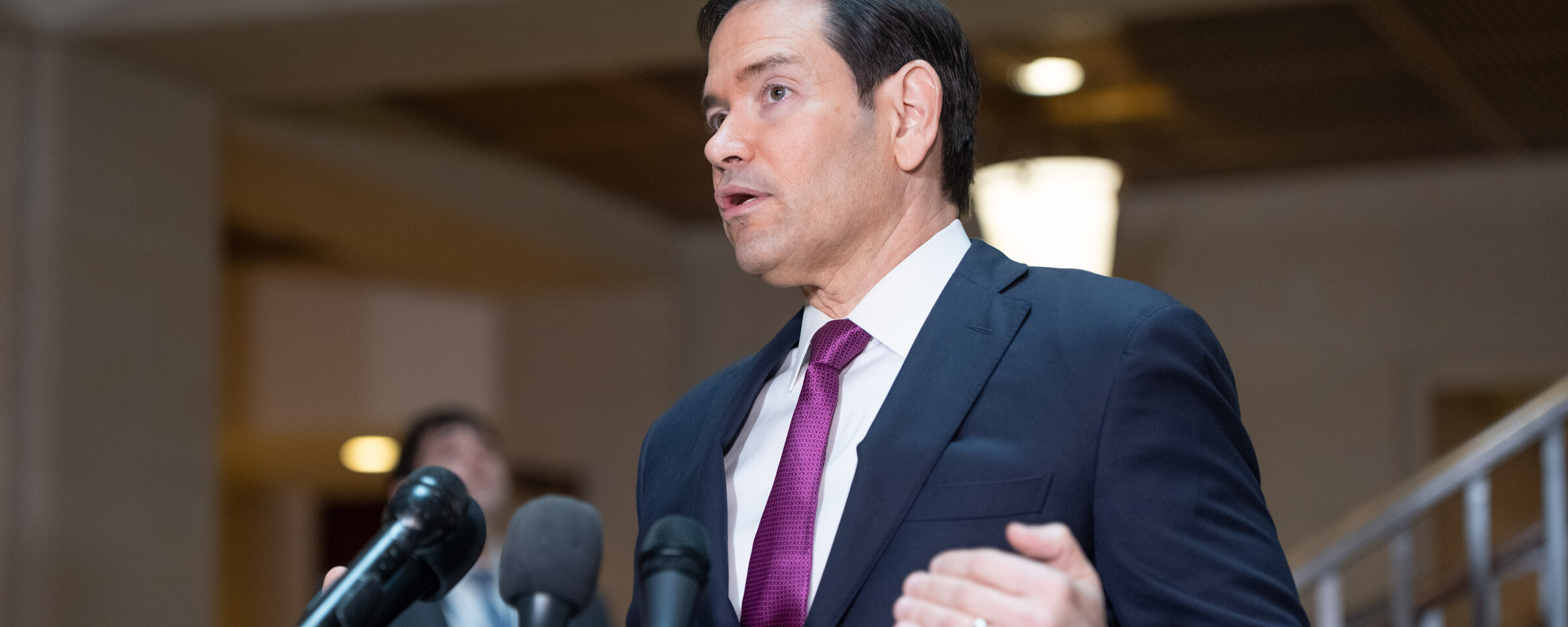Secretary of State Marco Rubio speaks into multiple microphones in Capitol Building basement