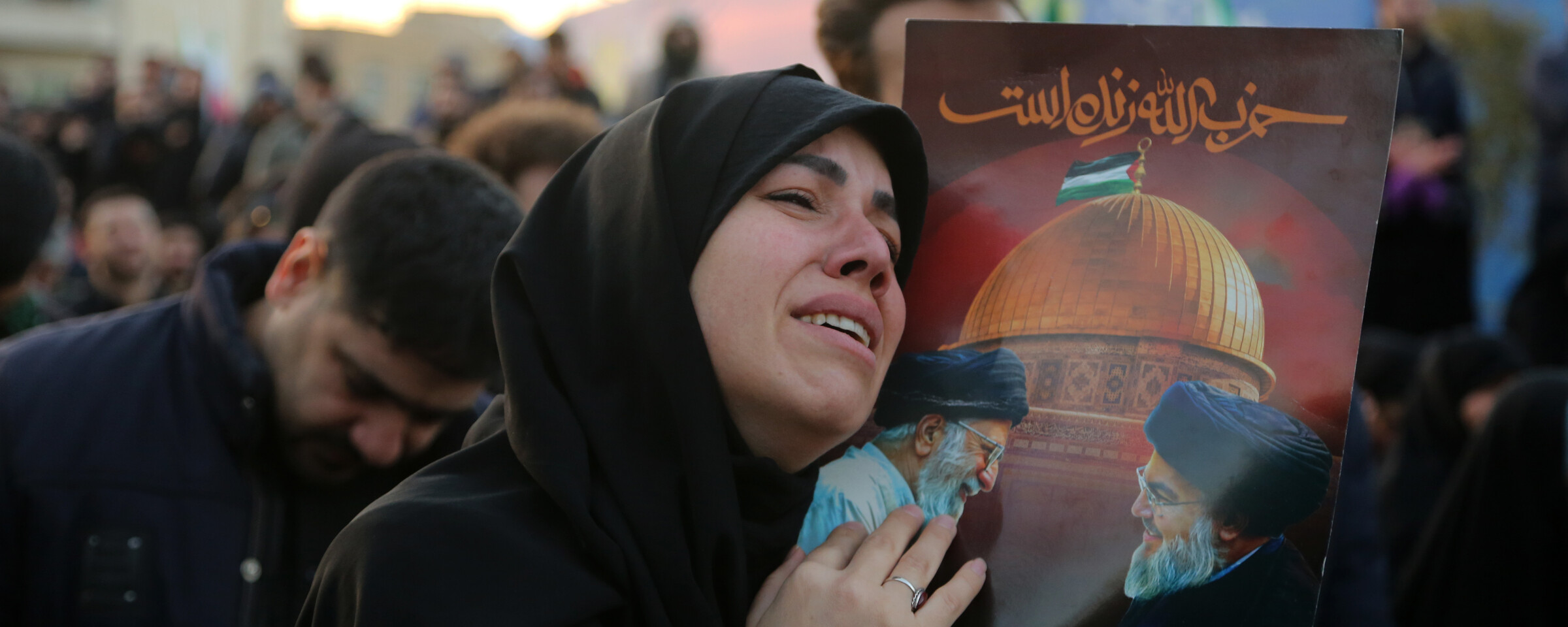 A woman embraces a portrait of Ali Khamenei