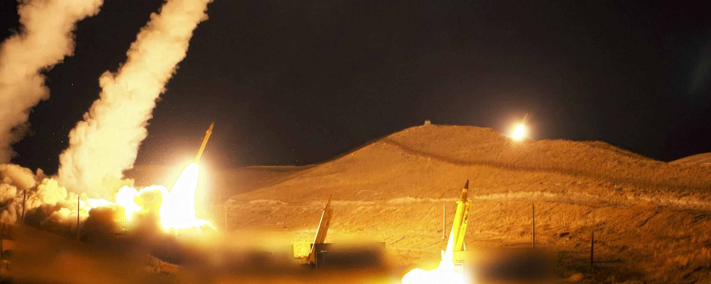 Several missiles launched at night trail smoke and fire