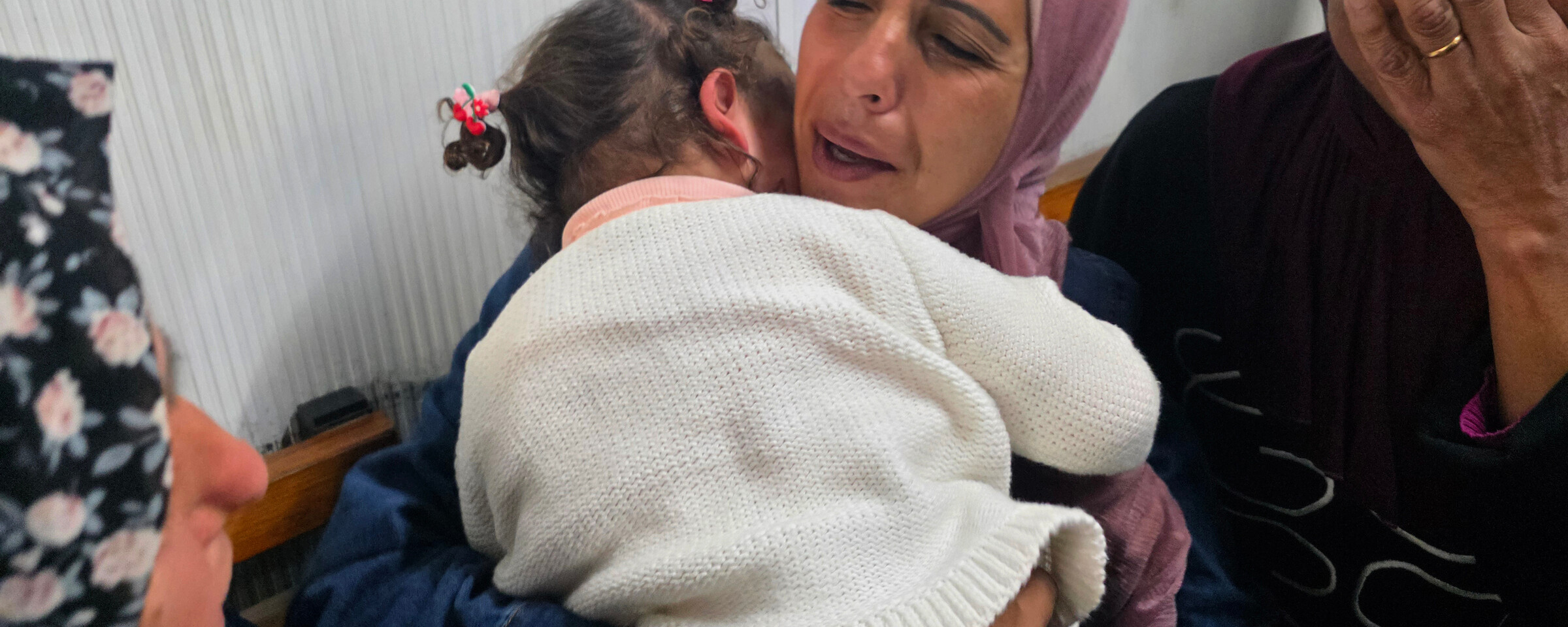A woman holds her toddler to her chest