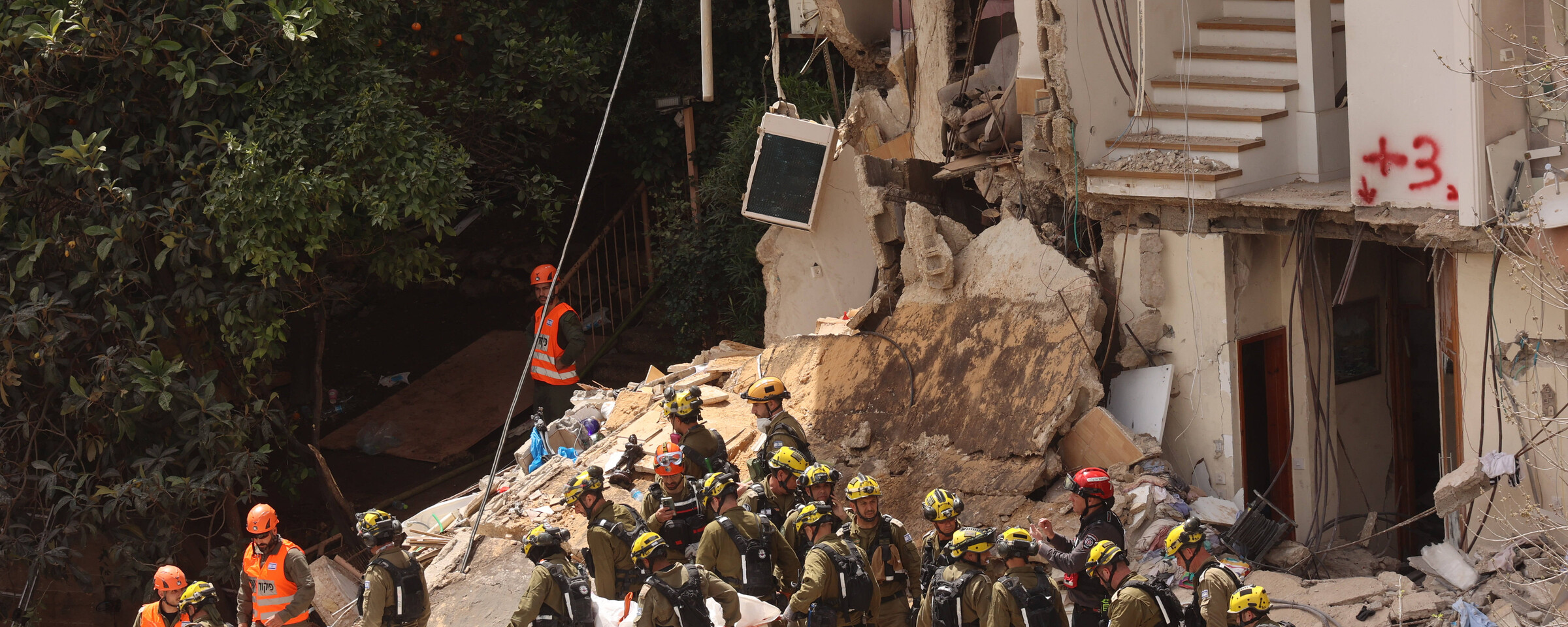 Group of men in helmets work in rubble