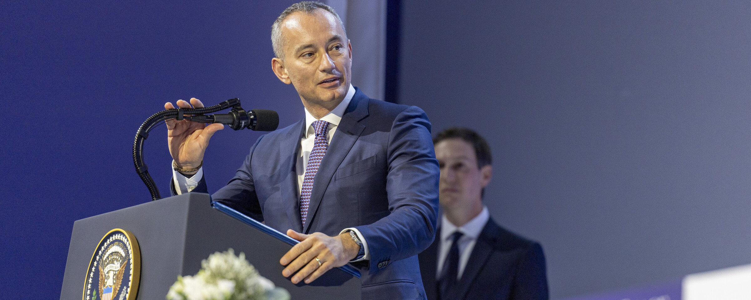 Man in suit speaks from a podium