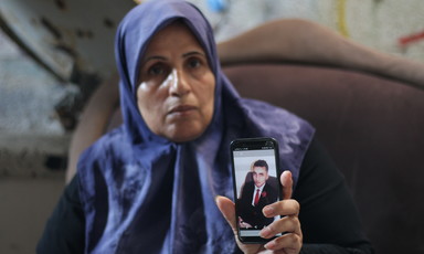 A Palestinian mother holds up a photograph on a phone of her son who died by suicide.