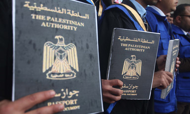 A group of men hold signs resembling passports with the words Palestinian Authority written on them