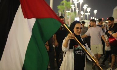 A woman in a crowd carries the Palestinian flag