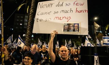 Demonstrators hold up a placard excoriating Israel's leaders for doing "so much harm to so many."