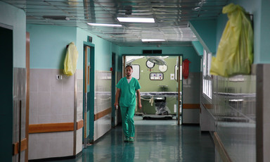 An employee of al-Shifa hospital in Gaza wearing green scrubs walks down a hospital corridor.
