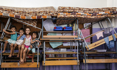 Children sit on stacked up furniture and mattresses
