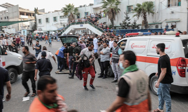 A medic carries an injured child beside the entrance to al-Shifa hospital in Gaza City