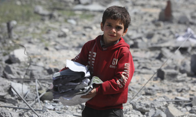 A boy stands amid the remains of a building that has been destroyed by Israel 