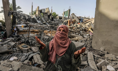 A woman stands in the middle of a home that has been destroyed in southern Gaza 