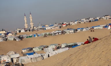 A daytime view of tents erected along a sandy desert hillside