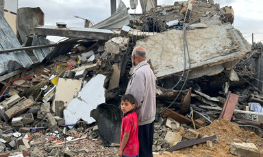 A boy and a man beside the remains of a building bombed by Israel 