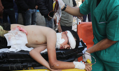 An injured young man with bandages on his body and head lies on his side