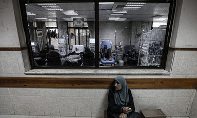 A woman sits below a window to a treatment room
