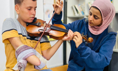 A one-handed boy practices violin with his teacher