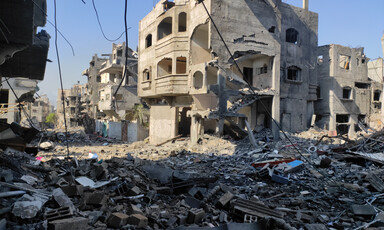 A daytime view of a destroyed building, rubble covering the street. 