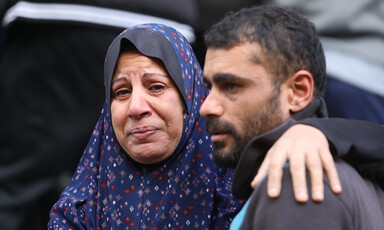 A woman in tears rests an arm around the shoulder of a young man