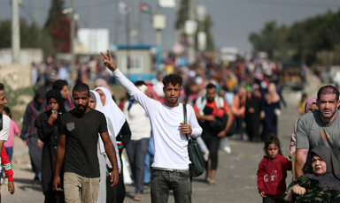 A young man in middle of street makes V for victory hand gesture