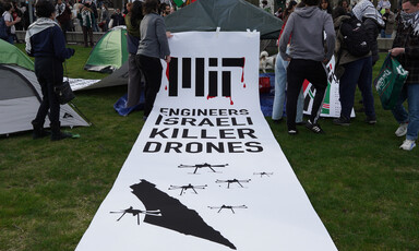 A banner on the ground at a student encampment reads MIT engineers Israeli killer drones