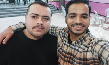 Selfie of two young men embracing while standing in wedding hall