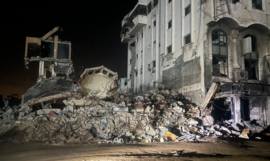 Floodlights at night shine on a building in ruins