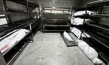 A room with metallic bunk beds, each shelf with a corpse wrapped in white