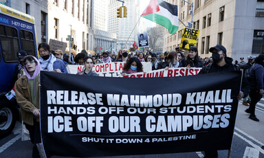 Protesters march with signs and a Palestinian flag