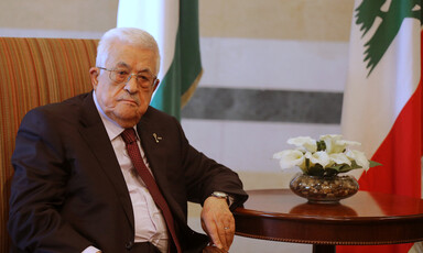 Mahmoud Abbas sits at a table next to some flowers