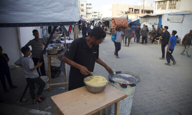 A man stands beside a bowl containing ingredients for falafel 