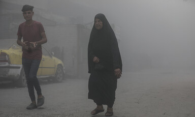 A young man and an older woman walk amid smoke following an Israeli airstrike on Gaza City