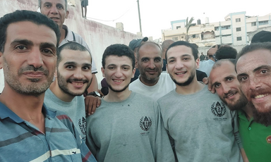 Eight men smiling and posing for a group photo