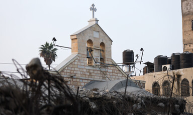 A church belfry beside a section of the church wall that has collapsed.