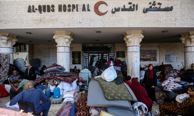 displaced people and their belongings in front of a hospital entrance
