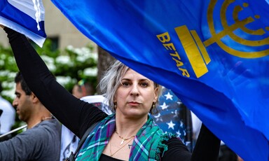 Portrait of a woman waving a Betar flag over her head at a demo