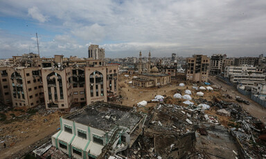 Several tents pitched in a severely destroyed campus with few buildings standing but damaged.