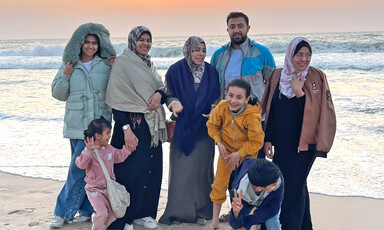 Portrait of a family standing on a beach in front of the sea during sunset