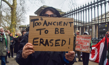 A person holds a sign reading "Too ancient to be erased" with museum and other protesters in background