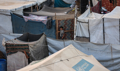 An aerial view of rows of tents with a child standing in the middle of them.