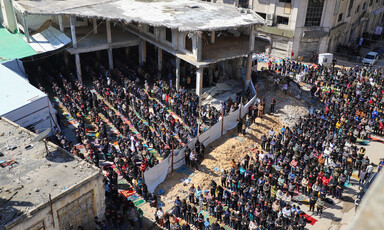 people pray in and around a largely destroyed mosque