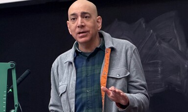 Ali Abunimah standing and speaking in front of a chalkboard