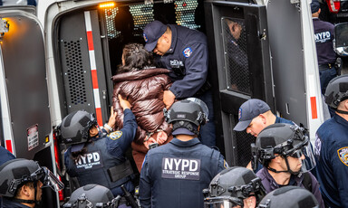 Two New York police officers place a woman in a van surrounded by many other police officers
